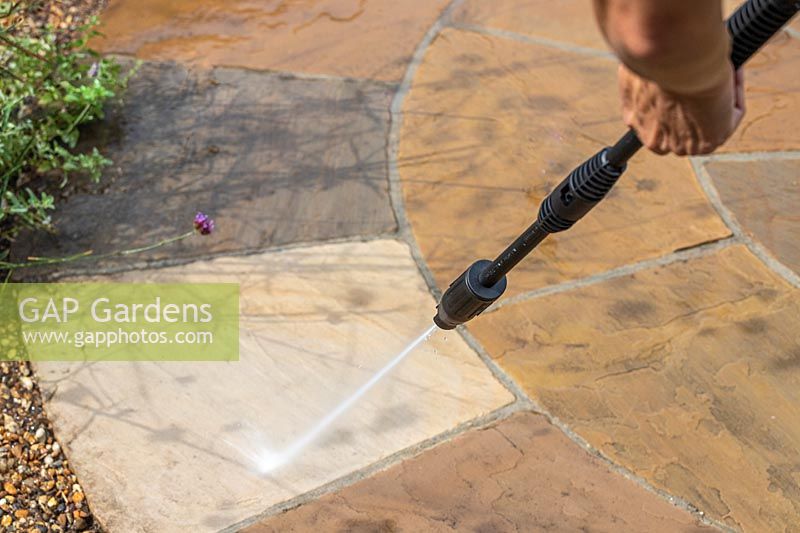 Woman using pressure washer to clean circular patio