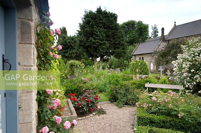 Small country cottage garden with parterre and gravel path leading to bench