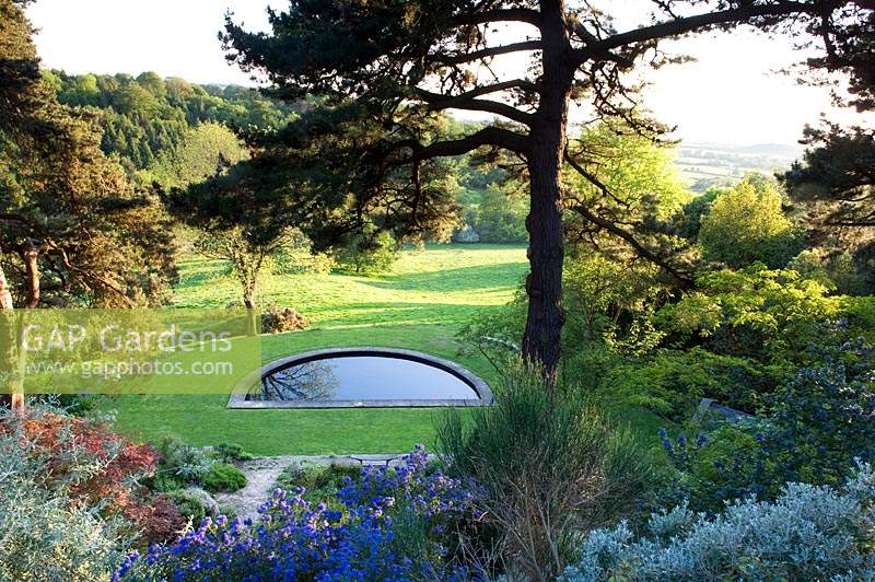 View over planting - Phormium, Clematis and Ceanothus to half moon water feature and countryside beyond. 