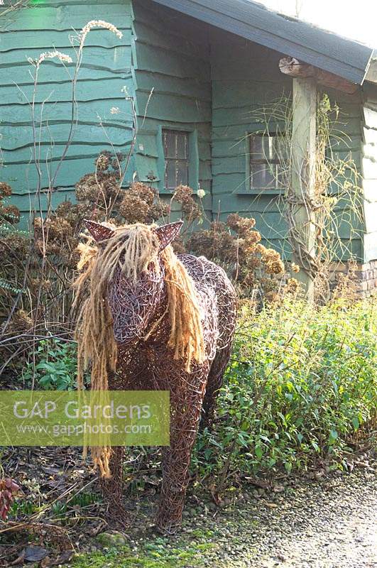 Woven pony sculpture by wooden shed