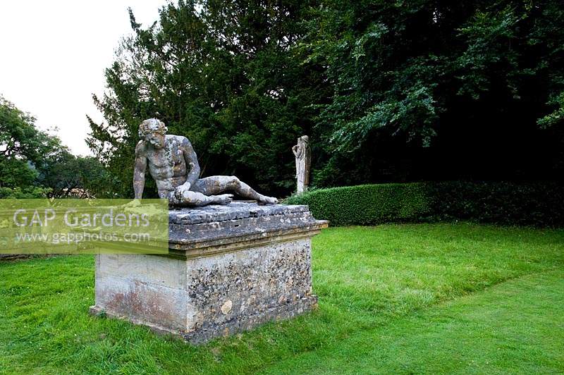 Statue of the dying gladiator on plinth, set on lawn