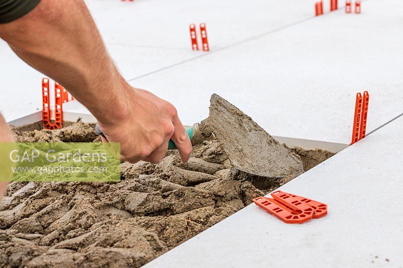 Man using a trowel to distribute cement evenly for laying a patio slab
