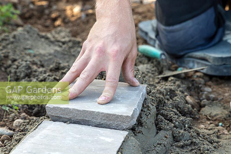 Man carefully laying sandstone setts on bed of cement