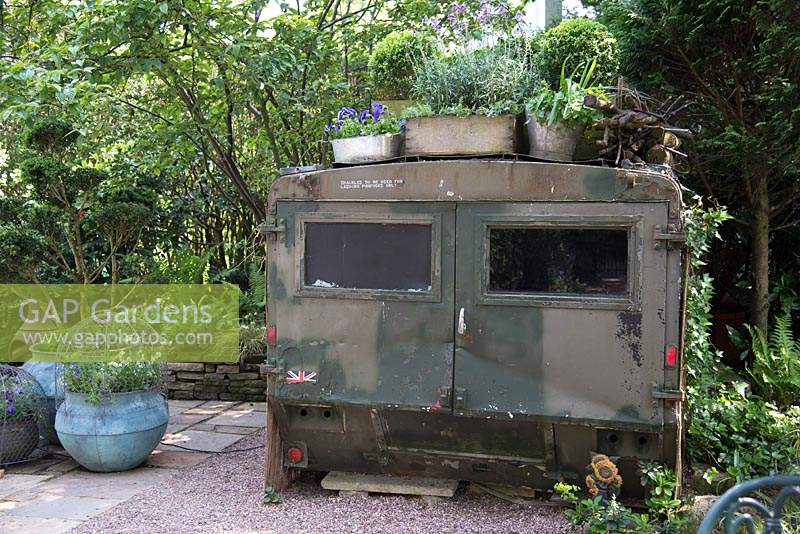 Unusual old military vehicle used as a shed in shaded small town garden
