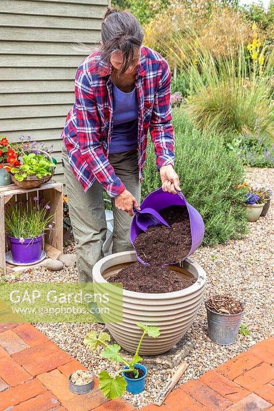 Woman adding fine garden compost to a large plastic planter