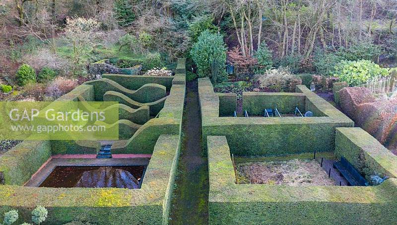 View over Reflecting Pool and Hedge Gardens. Formal hedges and columns of Taxus baccata. Veddw House Garden, Monmouthshire, Wales, UK. Garden designed and created by Anne Wareham and Charles Hawes.
