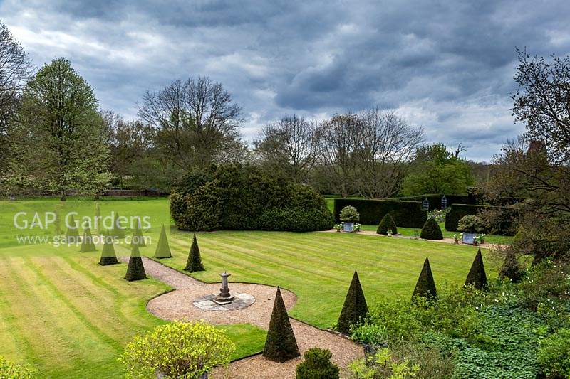 View of formal lawn with pyramids of yew, Taxus baccata and central sundial,