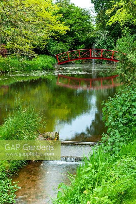 Stream flowing from lake with distant red bridge and waterfall beyond - Open Gardens Day, Nacton, Suffolk