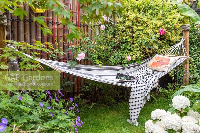 Hammock with cushion and blanket in small tropical garden