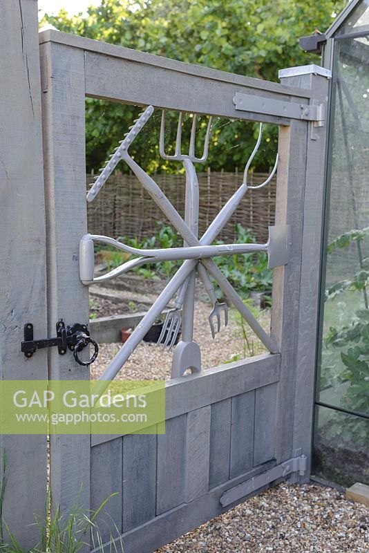 Gate with garden tools by garden designer George Carter, leading to the vegetable garden. 