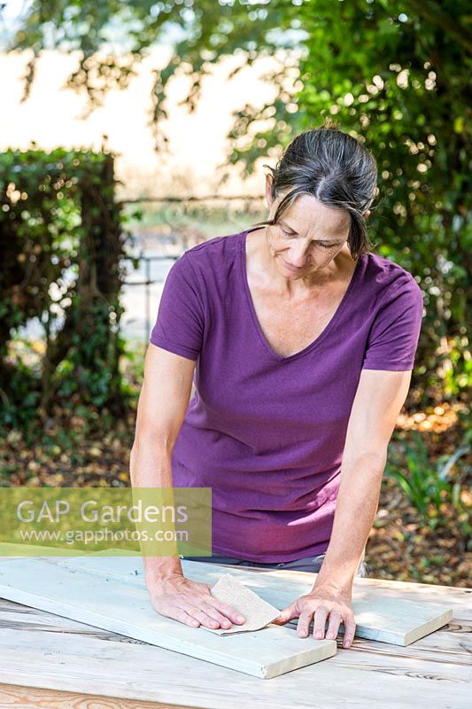 Woman using sandpaper to smooth the surface of the boards. 