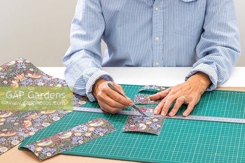 Woman using a craft knife and metal ruler to cut out panels of wrapping paper