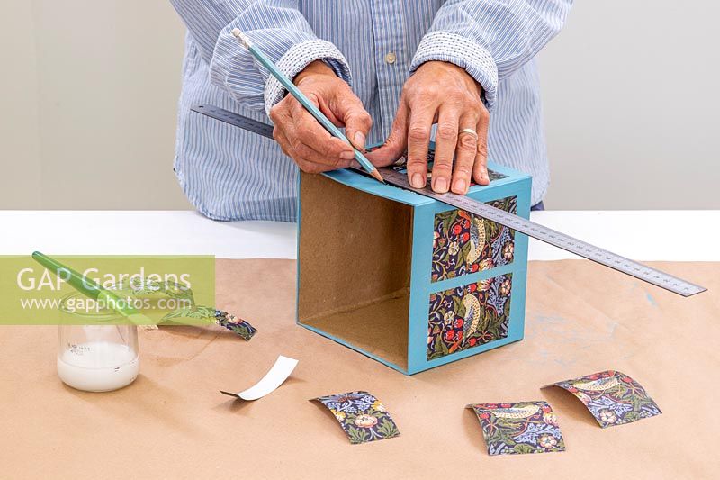 Woman using pencil and ruler to mark guides on cardboard box