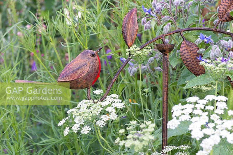 Metal bird sculpture amongst wild flowers