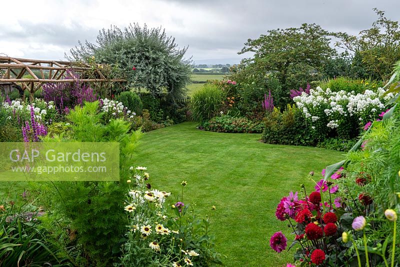 Looking out from a half-acre country garden over dahlias, lawns and borders of summer perennials, to a rural vista of Blackmore Vale with fields, spinneys and distant hills.