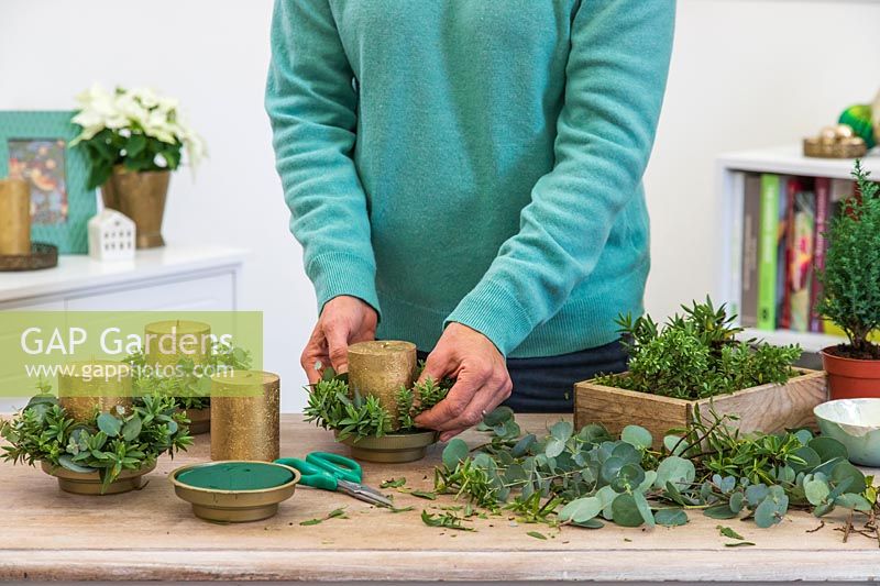 Woman adding a mix of Eucalyptus and Hebe to each candle holder. 