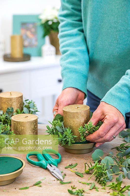 Woman adding a mix of Eucalyptus and Hebe to each candle holder