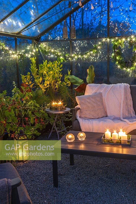 Lounge furniture inside greenhouse decorated for Christmas with fairylights and candles