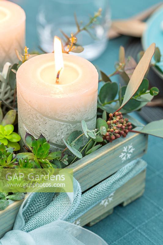 Close up of carved pillar candle in wooden advent box centerpeice on a dining table 