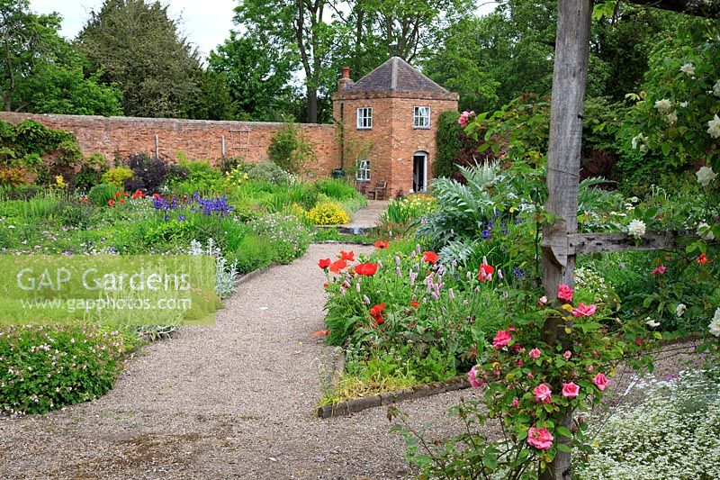 Borders and paths in front of the brick folly built in to the walls of the walled garden.
