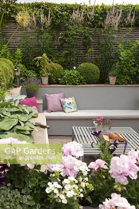  Cottage garden with built in benches and cushions, a metal table and raised beds