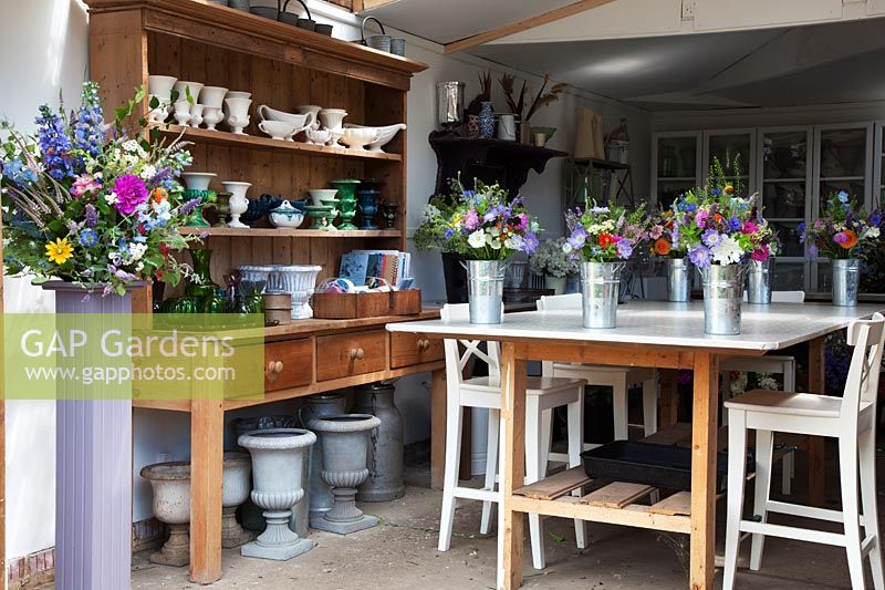 The flower arranging studio with wedding arrangements ready, collections of vases, urns and buckets.