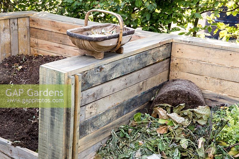 Compost heaps made from upcycled old wooden pallets - one bin with garden waste the other with ready to use compost and a small wooden trug with garden waste. RHS Grow Your Own with The Raymond Blanc Gardening School. RHS Hampton Court Flower Show July 2018 - Designers: Allister Dempster  and  Rossana Porta 