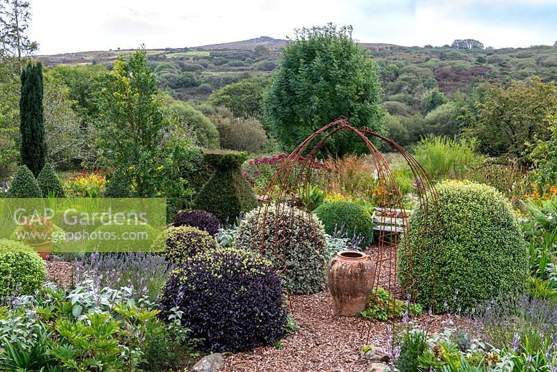 Small formal area of country garden with view to countryside beyond 