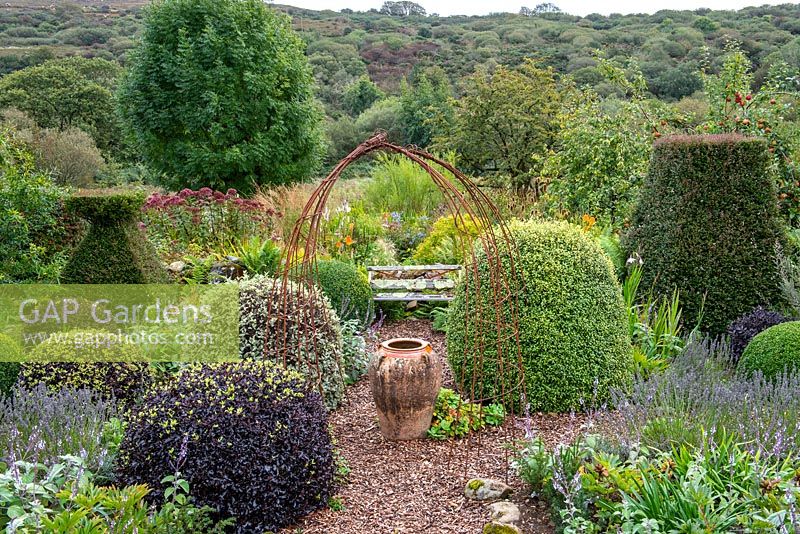 Small formal area of cottage garden with views of landscape beyond 