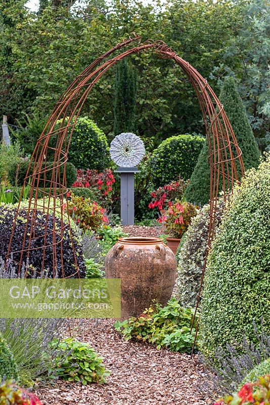 Small formal country garden with sculpture and ornaments as focal points 