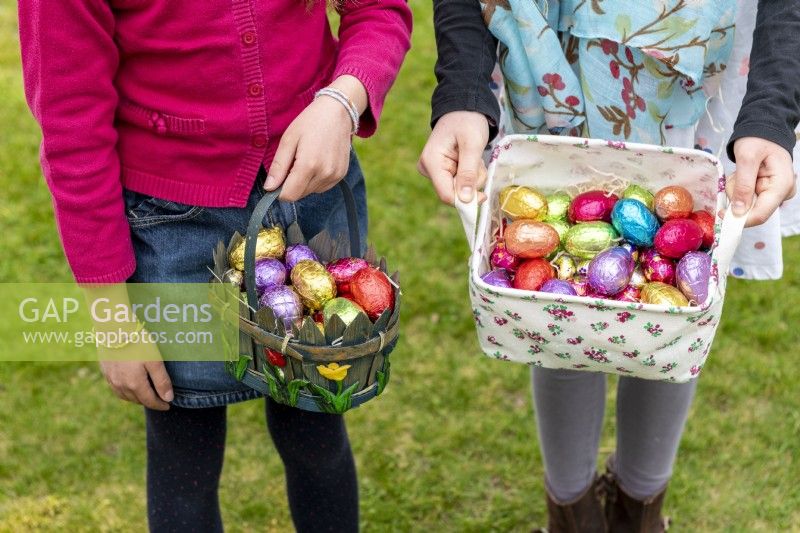 Children holding baskets with colourful chocolate eggs at Easter