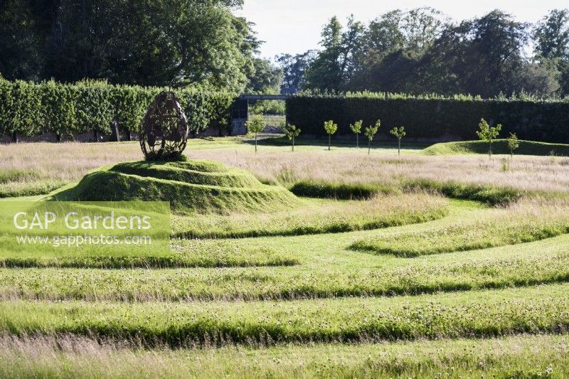 Grass maze with a spiral mound at its centre topped by a pear made of rusted garden implements at Gordon Castle Walled Garden, Scotland in July