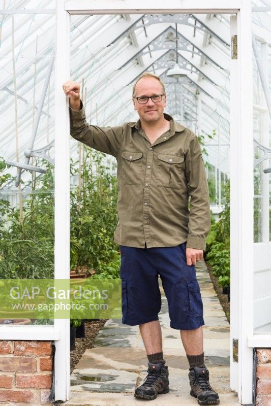 Man standing at entrance to greenhouse.