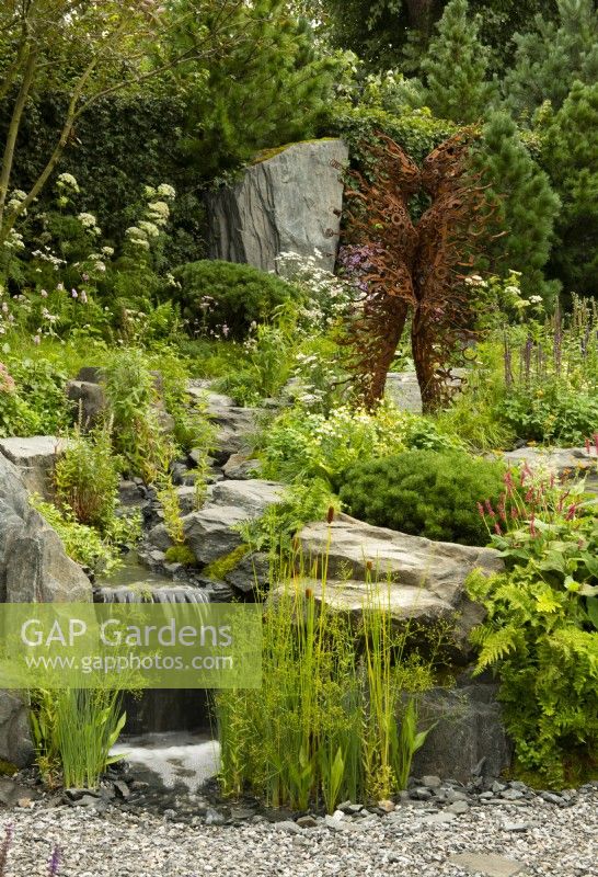 60 Degrees East, a garden between continents, a figurative metal sculpture beside a stream on a hillside surrounded by European and Asian planting.   Sculptures by Penny Hardy