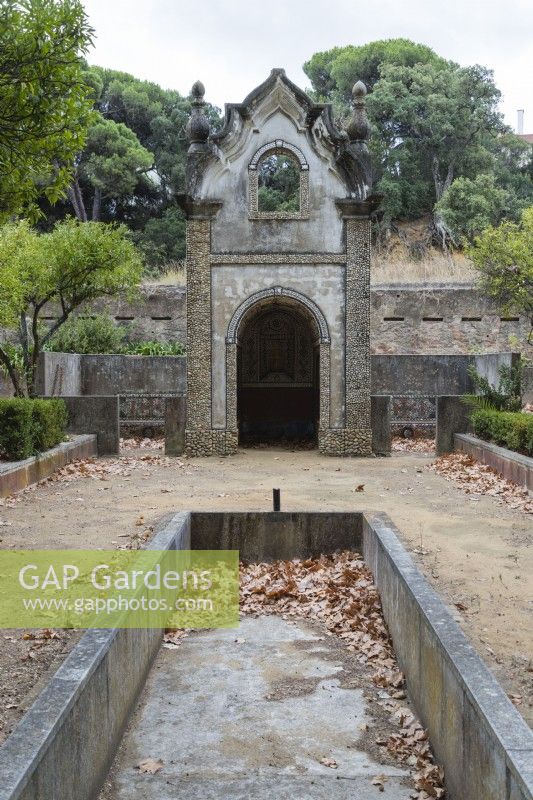 View to the Chapel - Capela. Ornate building. Pool in foreground with no water with leaf debris. Seixal, near Setubal, Portugal. September