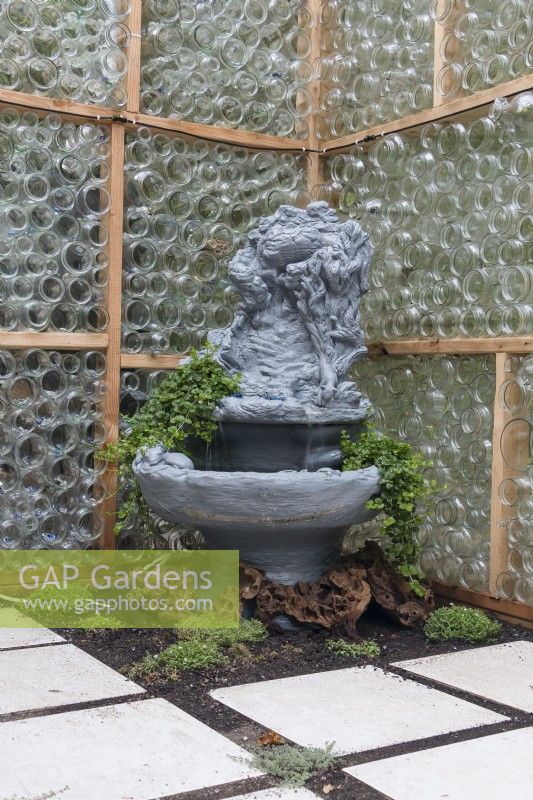 Fountain inside greenhouse made from recycled glass bottles provides humidity