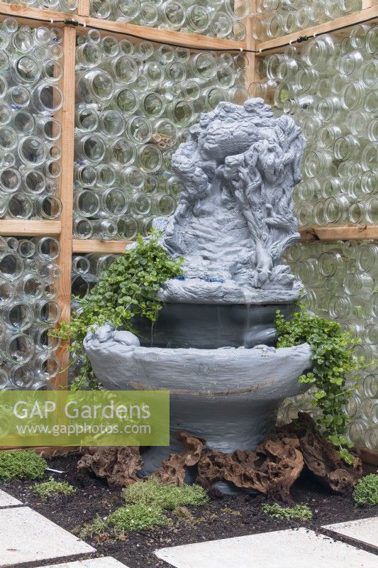 Fountain inside greenhhouse made from recycles glass bottles provides humidity