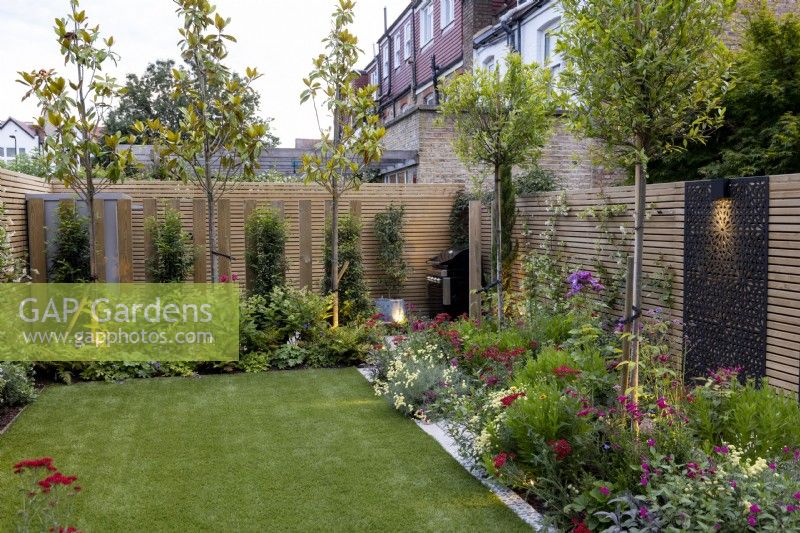 Contemporary suburban garden in London with colourful borders and lighting