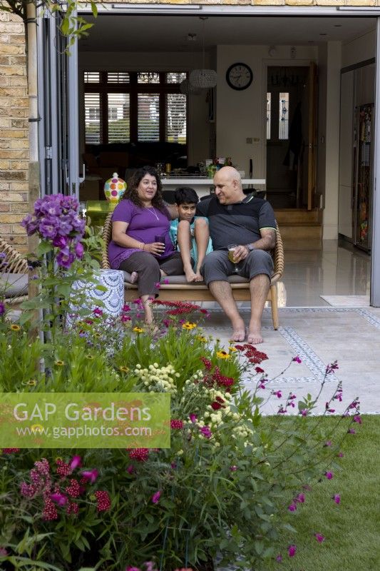 Couple and son sitting on patio in contemporary garden 
