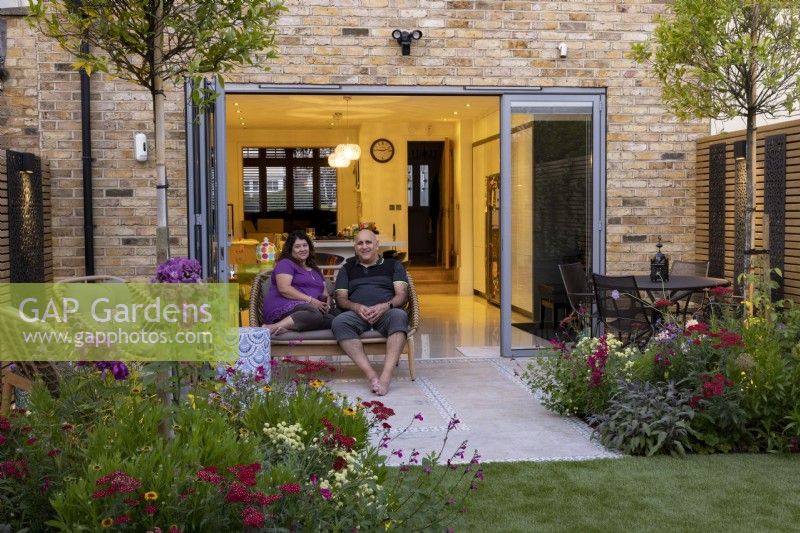 Couple sitting on patio in front of doors in a suburban garden