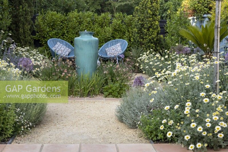 Contemporary gravel garden in suburban garden with tall ceramic container water feature