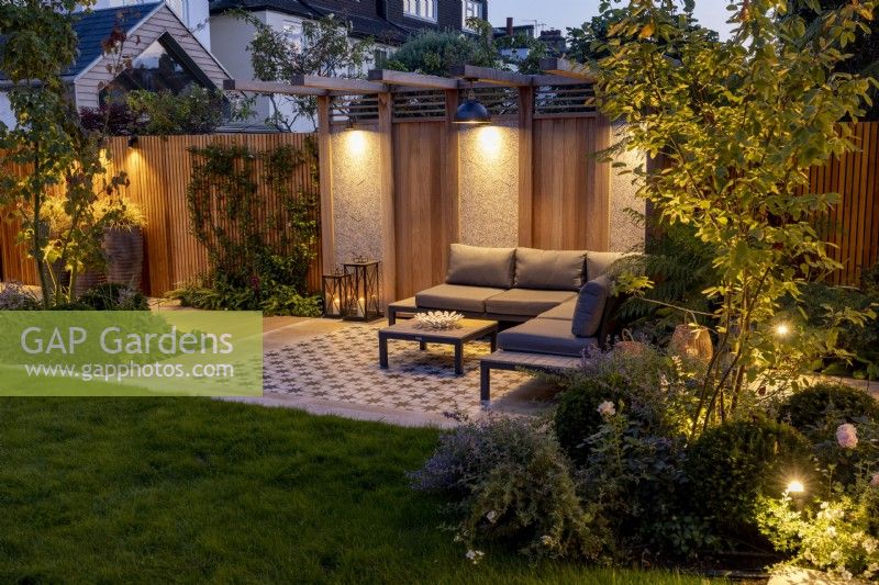 Modern garden with patio and pergola at night with lighting
