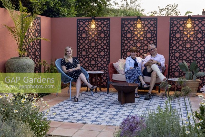 Family relaxing around a fire pit in their Moroccan style garden patio