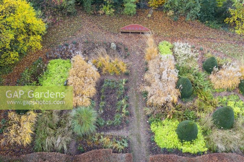 Large area of garden planted with several different ornamental grasses in blocks; image taken with drone. November. Autumn.