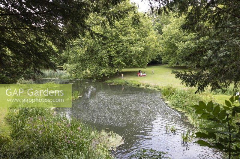 Visitors relaxing in the grounds of Audley End House, Essex by large pond