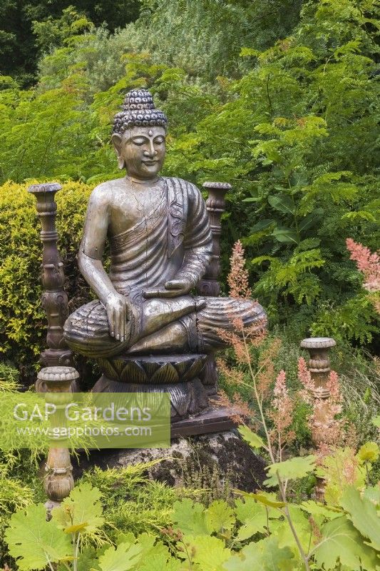 Silver Buddha statue in Zen garden in summer, Route des Gerbes d'Angelica Garden, Mirabel, Quebec, Canada - July