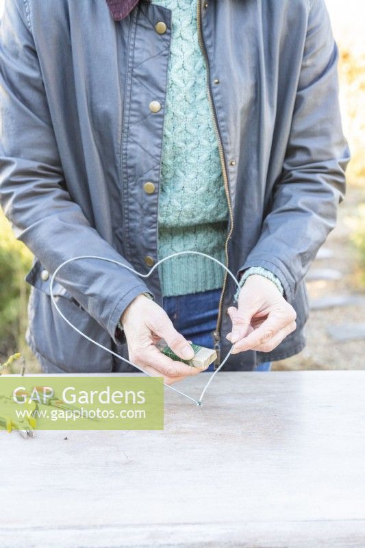 Woman using the thin wire to tie the two ends of thicker wire together