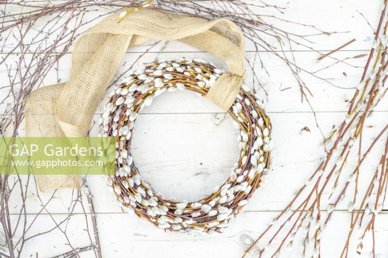 Homemade pussy willow wreath lying on wooden surface