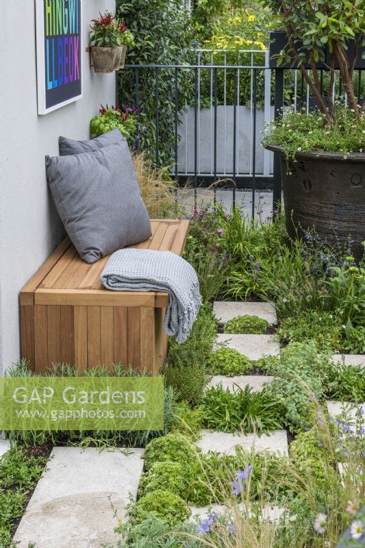 A balcony garden with a green floor created from paving slabs interspersed with herbs, succulents and perennials.