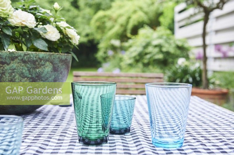 blue glasses on the tablecloth with view into the garden